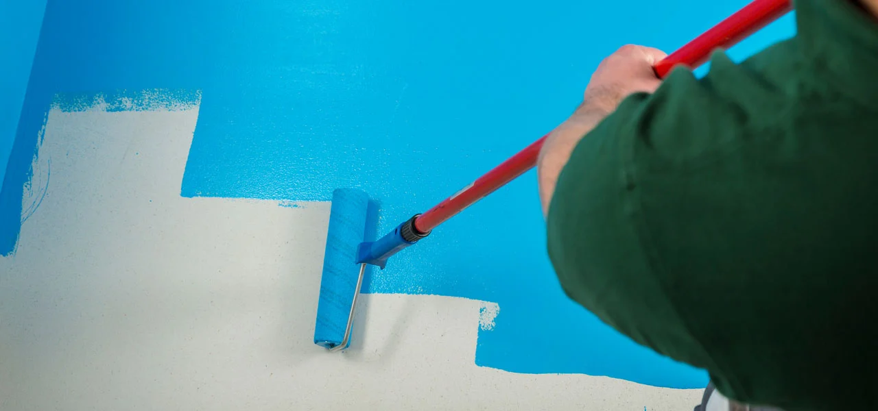 Blau Schwimmbadfarbe wird mir einer Farbwalze aufgetragen