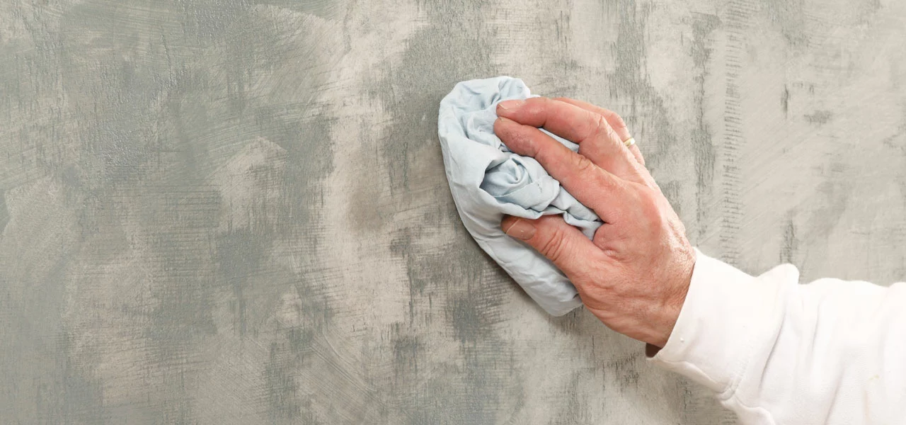 Die überschüssige Wachsseife wird mit einem Baumwolltuch von einer Wand abgerieben