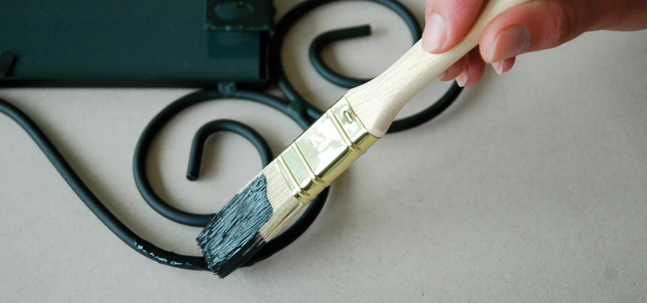 Schwarzer Kunstschmiedelack wird mit einem Pinsel aufgetragen