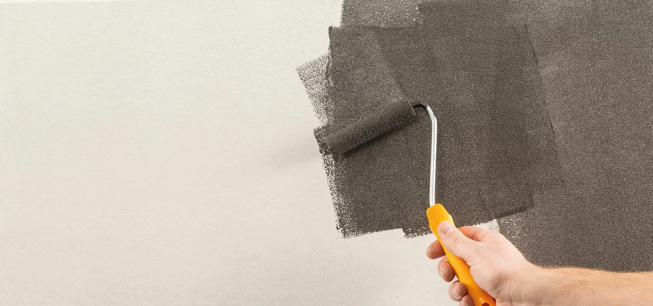 Rost-Grundfarbe in einem schwarzen Farbton wird mit einer Walze aufgetragen 