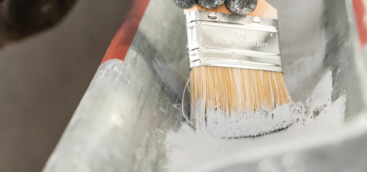 Dachrinne wird mit einem Pinsel gestrichen 