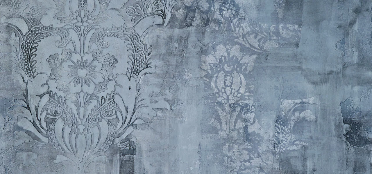Eine graue, mit dem Kalkputz Calce Argilla verputzte Wand mit Blumenornamenten