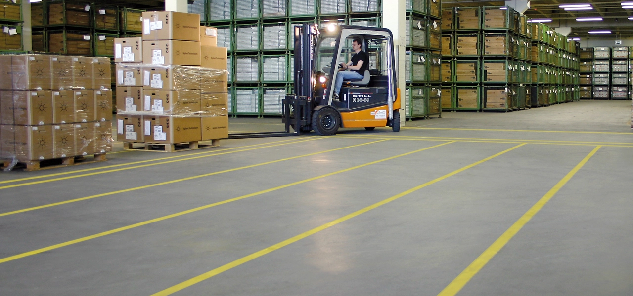 Lagerhallenboden, welcher mit gelbem Markierungsspray markiert wurde.