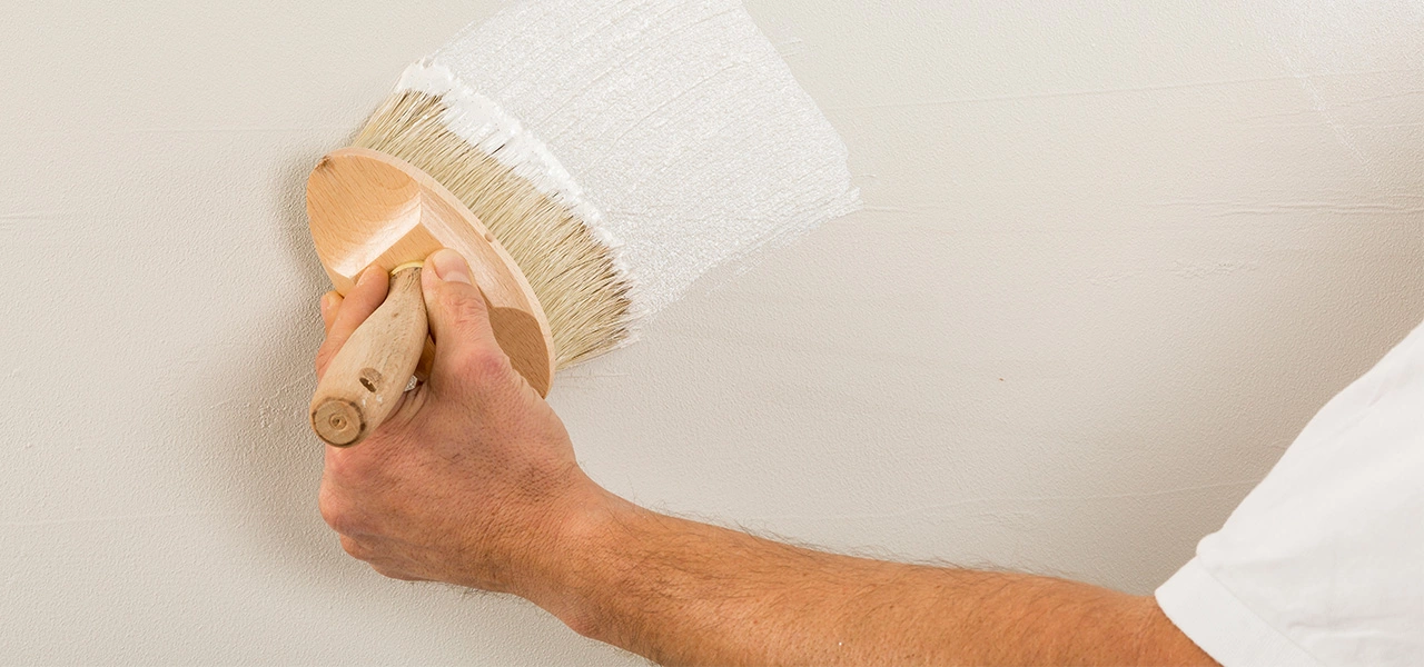 Metallische Wandfarbe in Silber, wird in Kreuzgängen mit einem großen Pinsel aufgetragen 
