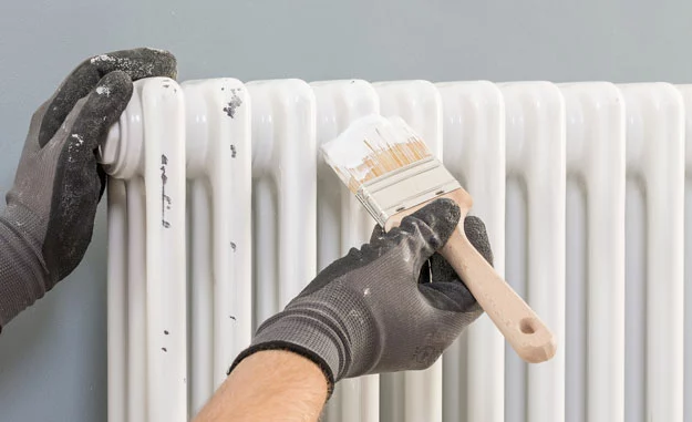 Der Heizkörper wird mit einem Pinsel gestrichen