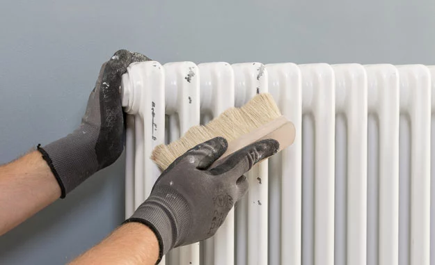 Die Heizung wird vor dem Streichen mit einer Bürste gereinigt