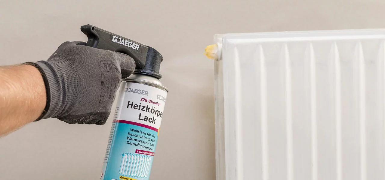 Weißer Heizkörper wird mit Sprühdose lackiert